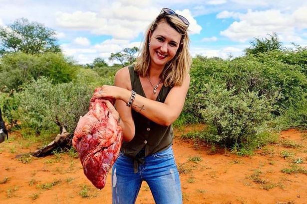 Trophy hunter poses with the heart of giraffe she just shot